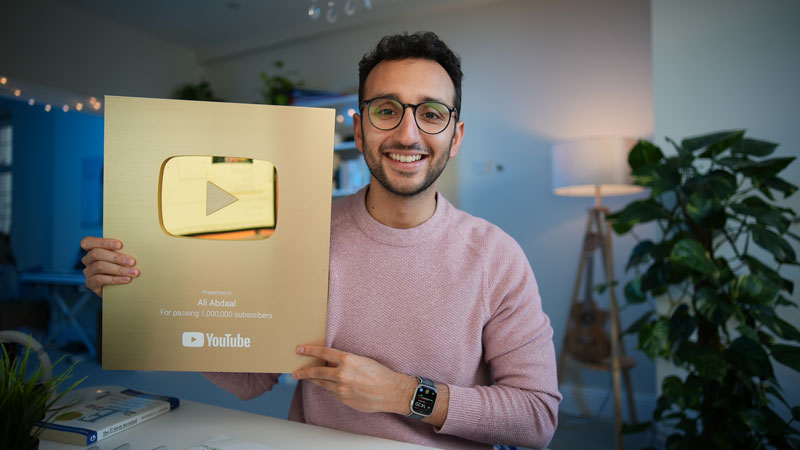 Featured image for the article 'how to start a youtube channel'. The image is a picture of Ali Abdaal smiling and holding up a gold YouTube play button