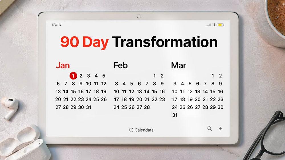 ipad displaying a calendar with months January, February and March displayed. A heading reads 90 day transformation. The ipad is on a table with some airpods, glasses and coffee